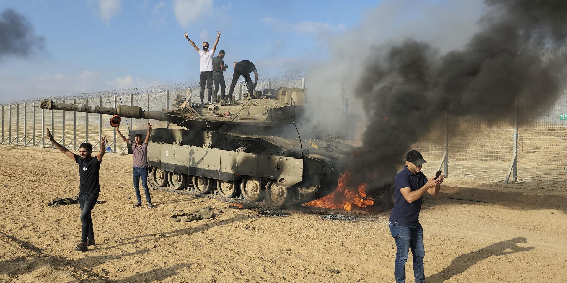 Палестинцы ликуют возле уничтоженного израильского танка рядом с ограждением сектора Газа  в субботу, 7 октября 2023 года - ИноСМИ, 1920, 11.10.2023