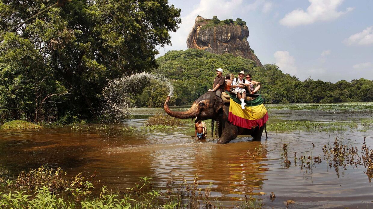 Ручной слон обрызгивает водой иностранных туристов во время сафари в Сигирии, примерно в 100 километрах к северо-востоку от Коломбо, столицы Шри-Ланки. 2 декабря 2011 года