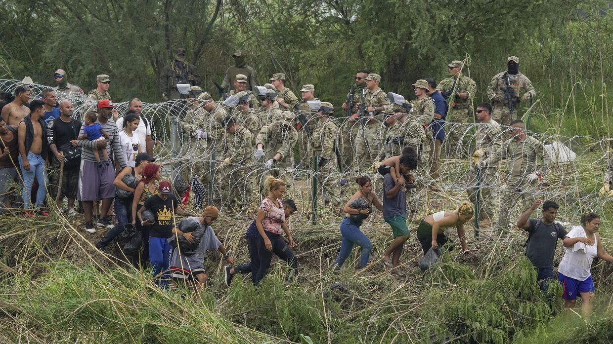 Национальные гвардейцы штата Техас укрепляют полосу колючей проволоки на берегу Рио-Гранде в то время, когда мигранты пытаются проникнуть в США. 11 мая 2023 года