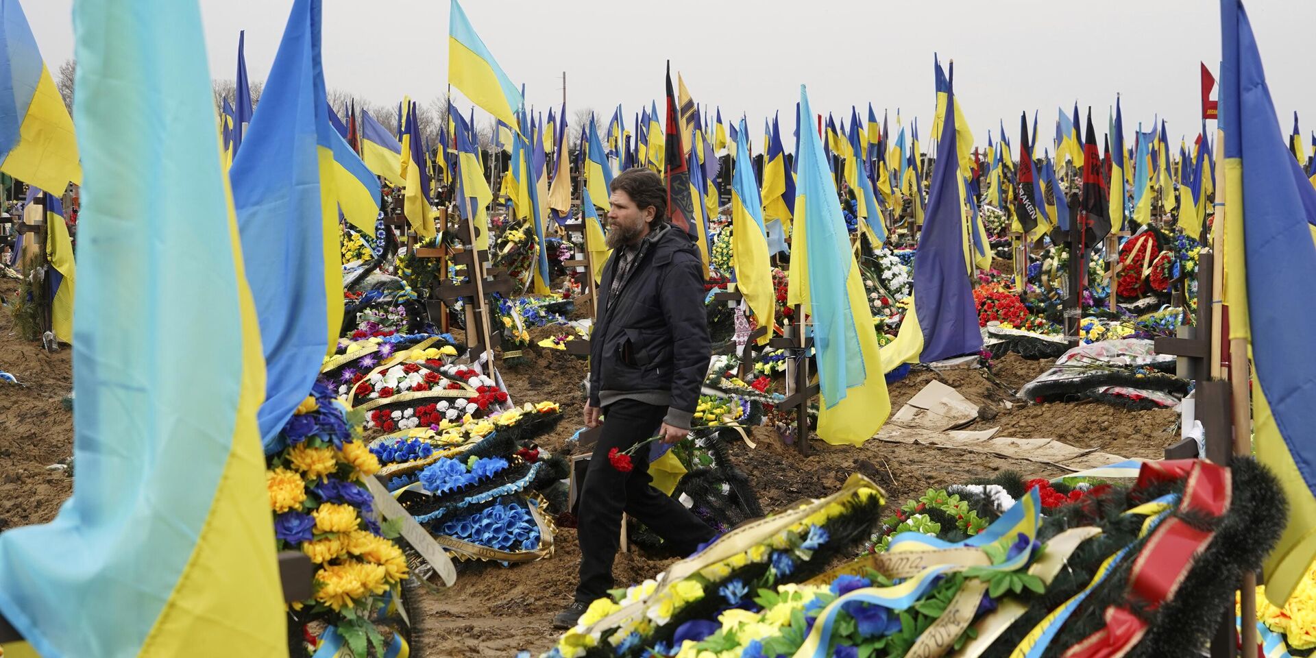 Мужчина несет цветы, чтобы возложить их к могиле убитого солдата на городском кладбище в Харькове, Украина - ИноСМИ, 1920, 12.02.2024