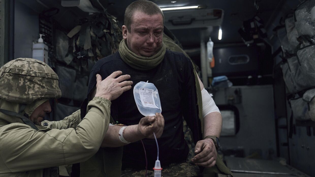Украинский военный медик оказывает первую помощь раненному в бою солдату