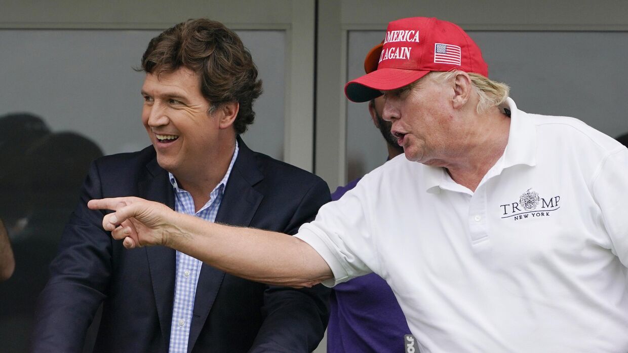 Такер Карлсон и бывший президент Дональд Трамп беседуют, наблюдая за игроками в гольф