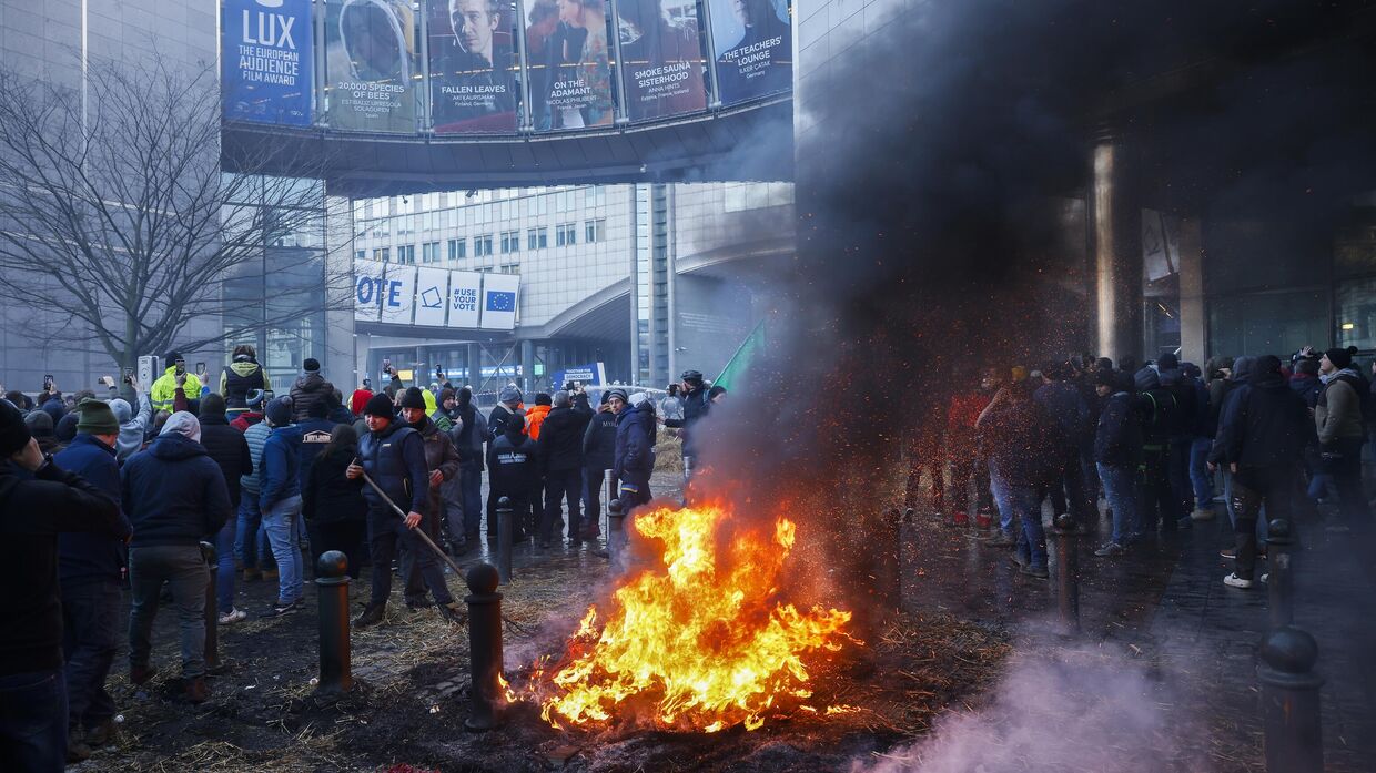 Фермеры сжигают солому и шины во время акции протеста у здания Европейского парламента в Брюсселе, где европейские лидеры собрались на саммит ЕС 1 февраля 2024 года