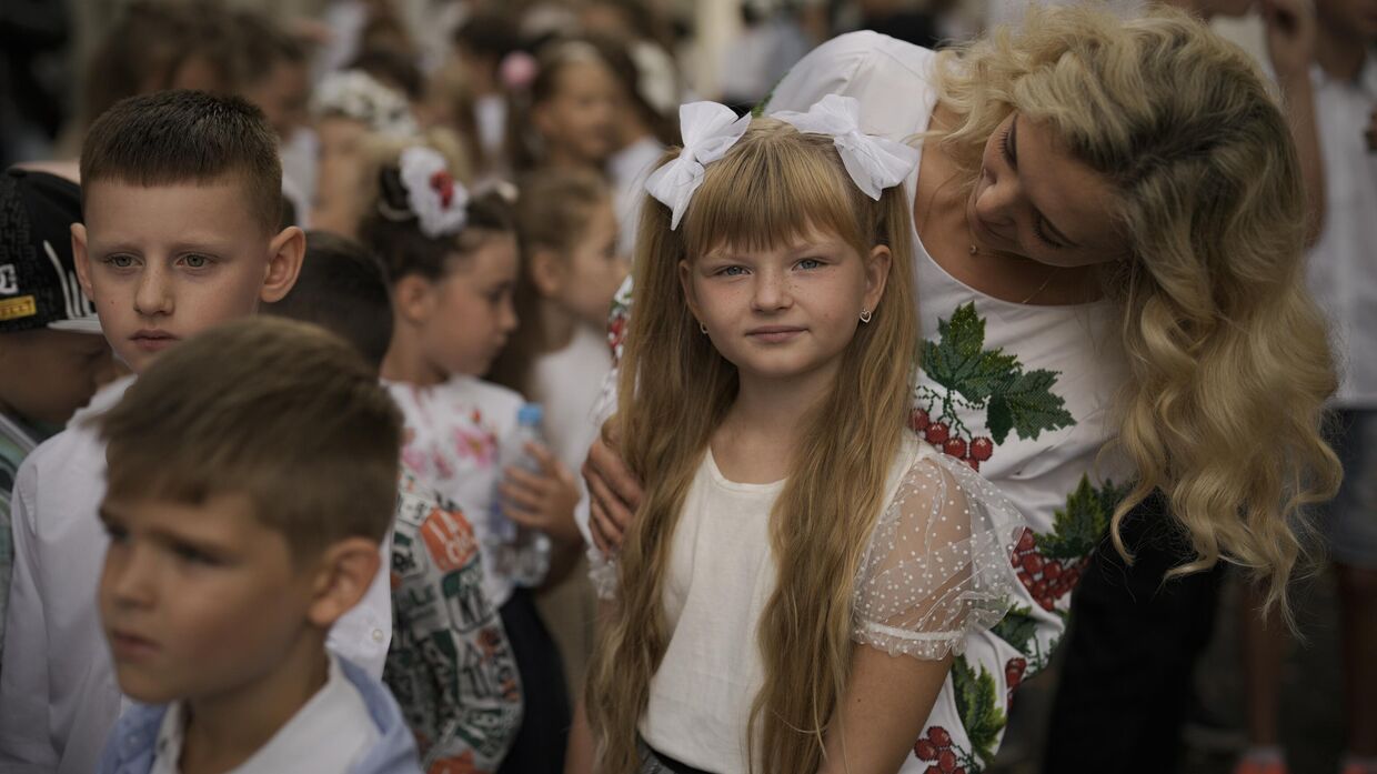 Учительница беседует с девочкой-беженкой с Украины перед церемонией открытия школы в Бухаресте, Румыния. 1 сентября 2022 года