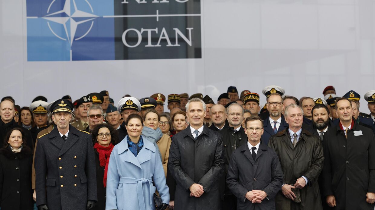 Генеральный секретарь НАТО Йенс Столтенберг, в центре, премьер-министр Швеции Ульф Кристерссон, справа от него, и наследная принцесса Швеции Виктория, слева от него, позируют с военными и штабным персоналом после церемонии по случаю вступления Швеции в НАТО