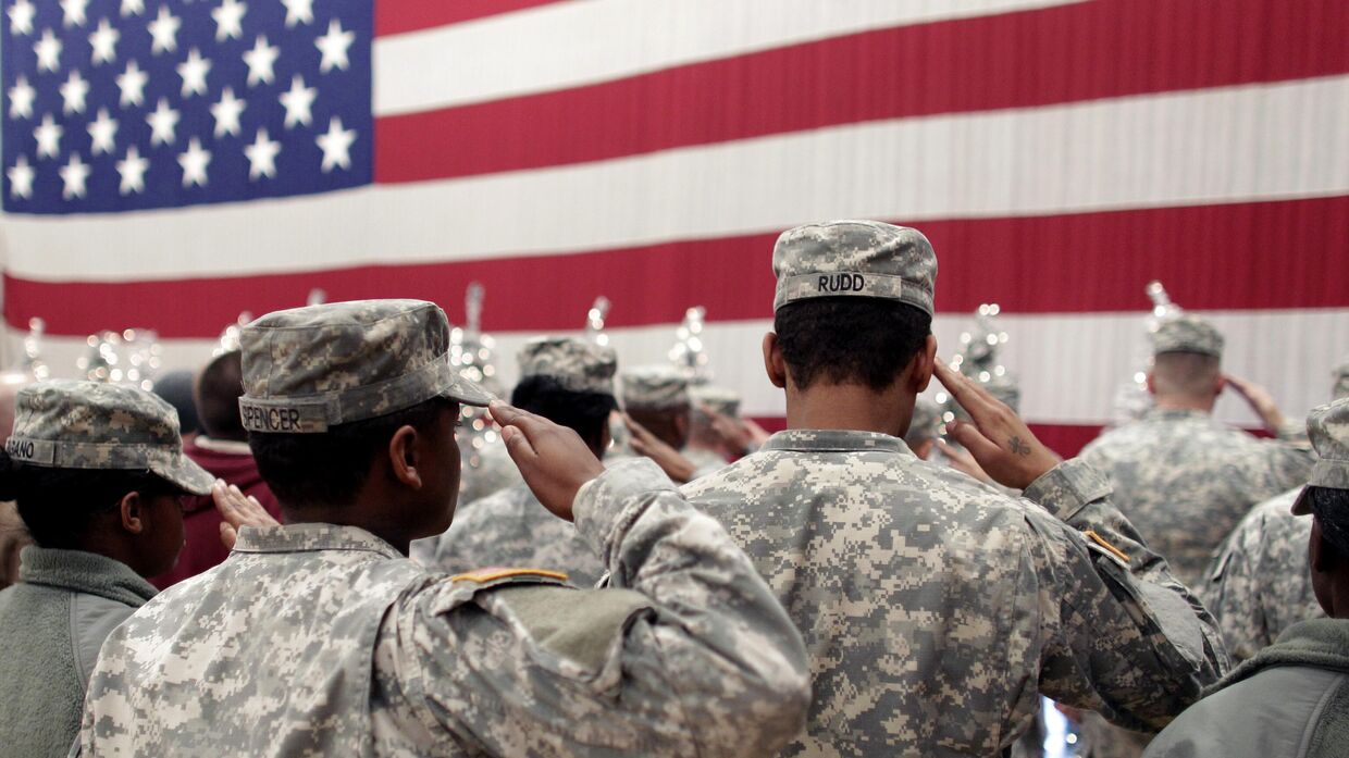Солдаты салютуют флагу США на церемонии приветствия возвращающихся домой из Афганистана