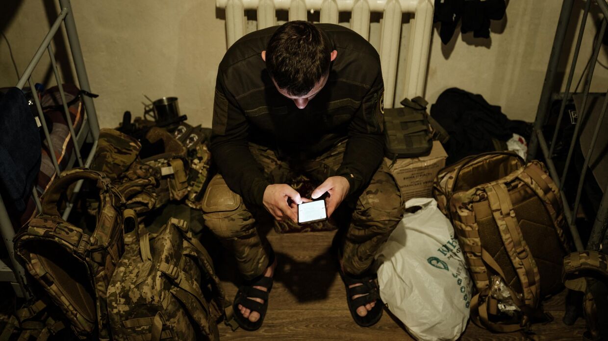Украинский военнослужащий пользуется интернетом на своем смартфоне
