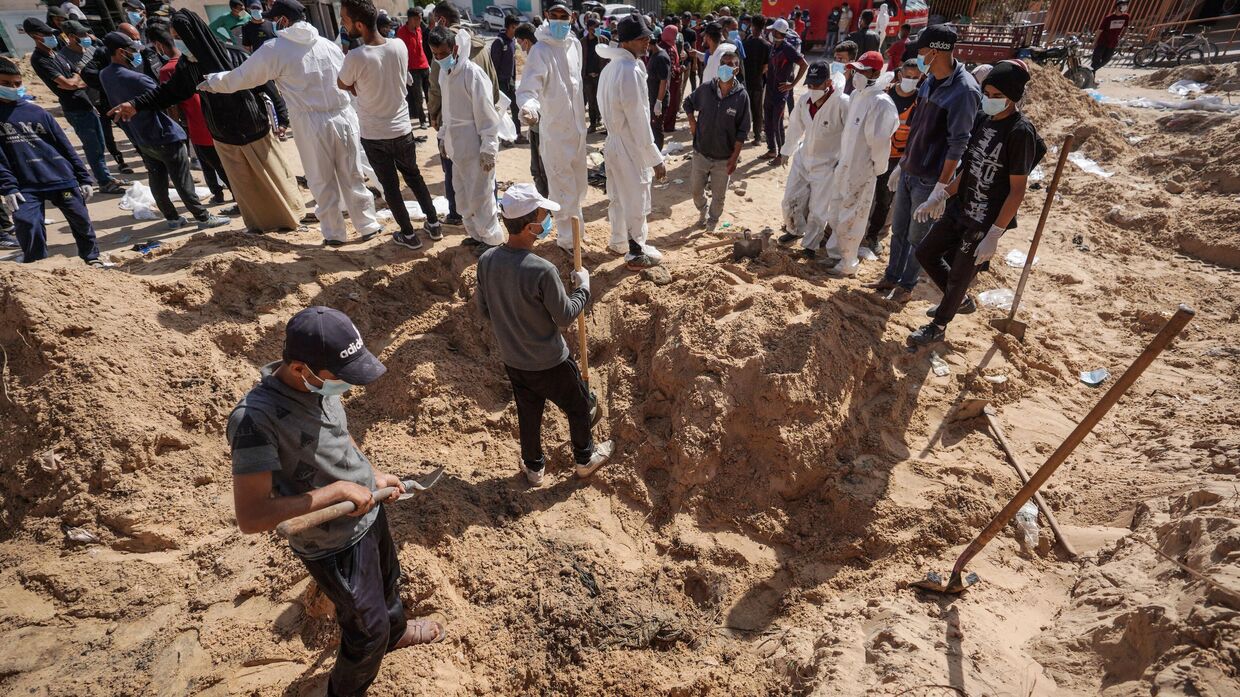 Палестинские работники здравоохранения раскапывают тела, похороненные израильскими войсками на территории больницы Насера в Хан-Юнисе на юге сектора Газа