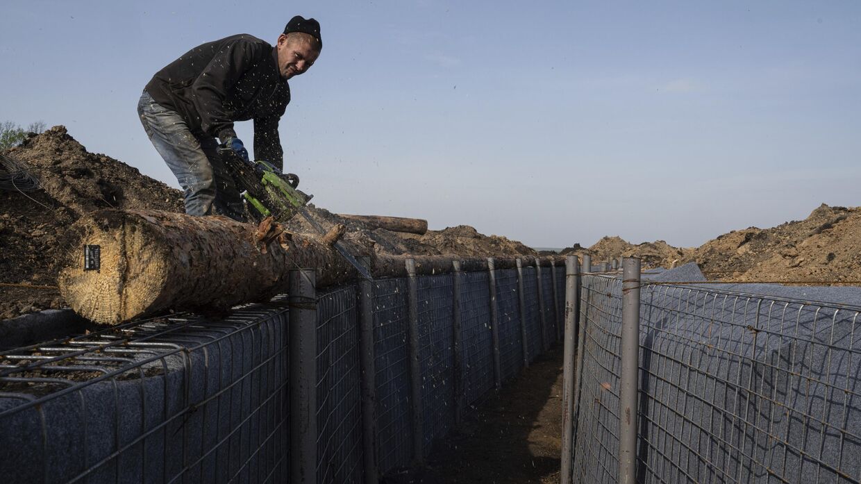 Рабочий строит оборонительные позиции в Харьковской области, Украина