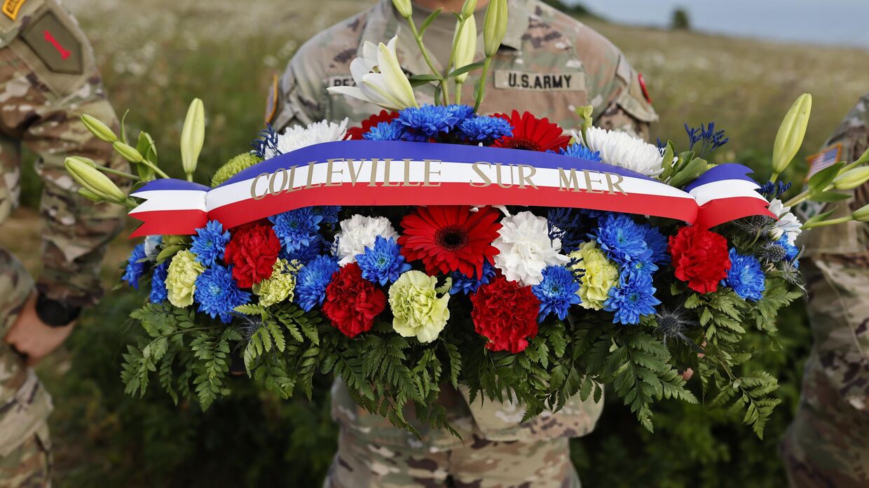 Американский солдат держит венок из цветов во время церемонии возложения венков к памятнику 1-й пехотной дивизии в рамках церемоний, посвященных 80-й годовщине Дня Д недалеко от пляжа Омаха, Нормандия