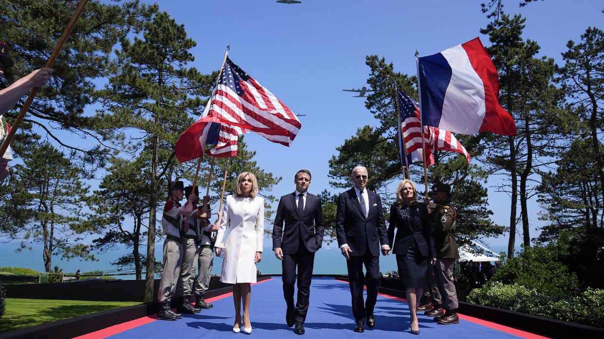 Президент США Джо Байден, первая леди Джилл Байден, президент Франции Эммануэль Макрон и его жена Брижит Макрон идут по сцене во время церемонии, посвященной 80-й годовщине высадки союзников в Нормандии, 6 июня 2024 года