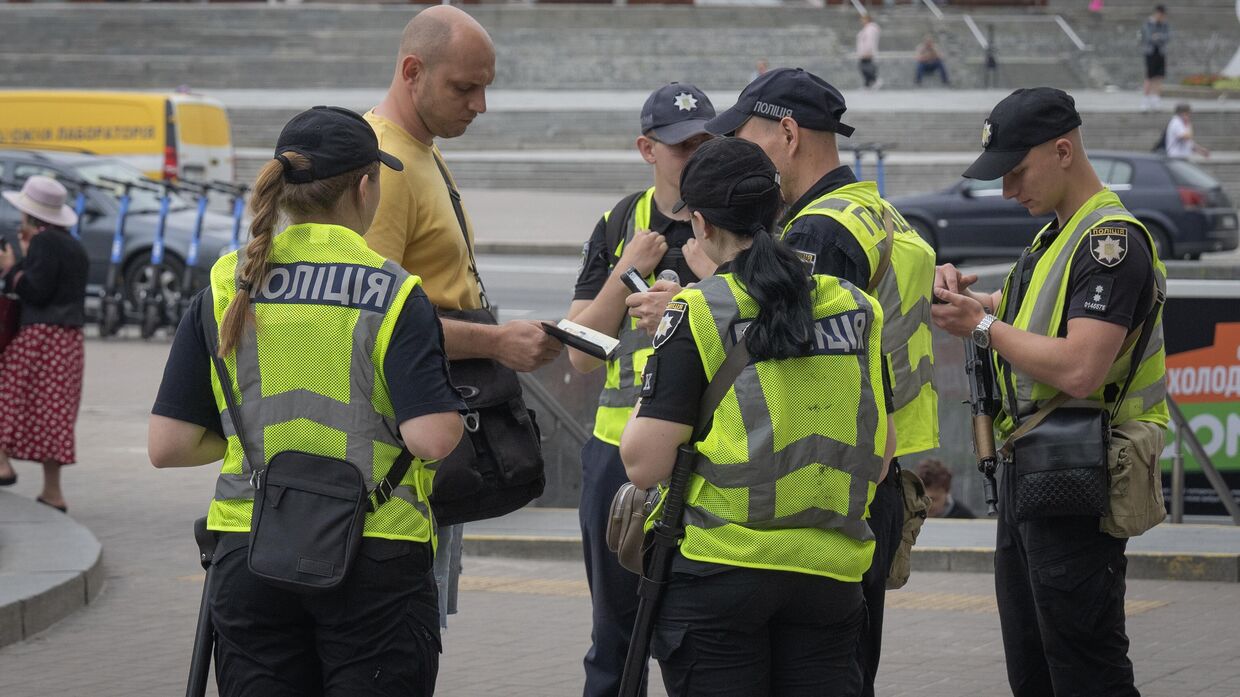 Сотрудники украинской полиции проверяют документы у мужчины, разыскивая тех, кто уклоняется от мобилизации
