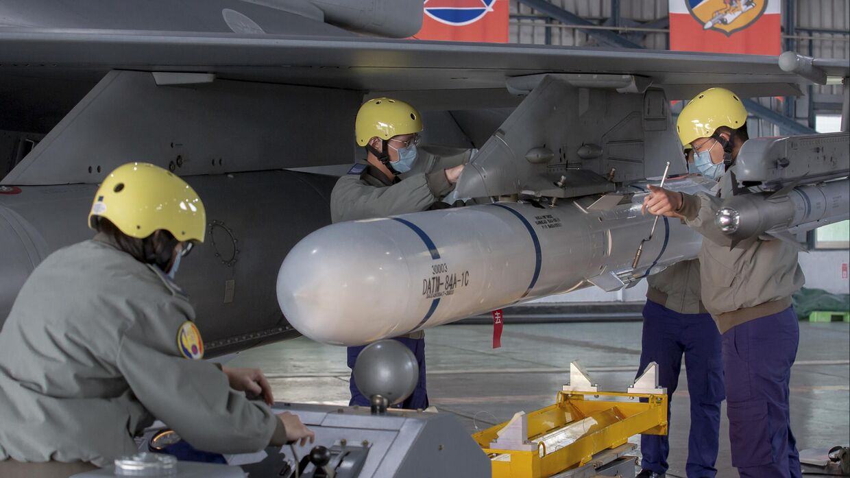 Бригада наземного обслуживания прикрепляет ракету к крылу реактивного истребителя F-16 на базе ВВС в Чиайи, Тайвань. 6 января 2023 года.
