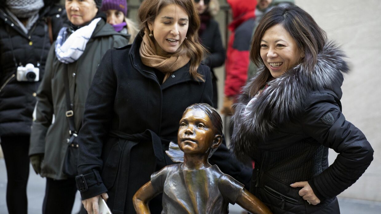Люди позируют со статуей Бесстрашной девчонки после ее переезда на новое место перед зданием Нью-Йоркской фондовой биржи. 10 декабря 2018 года.