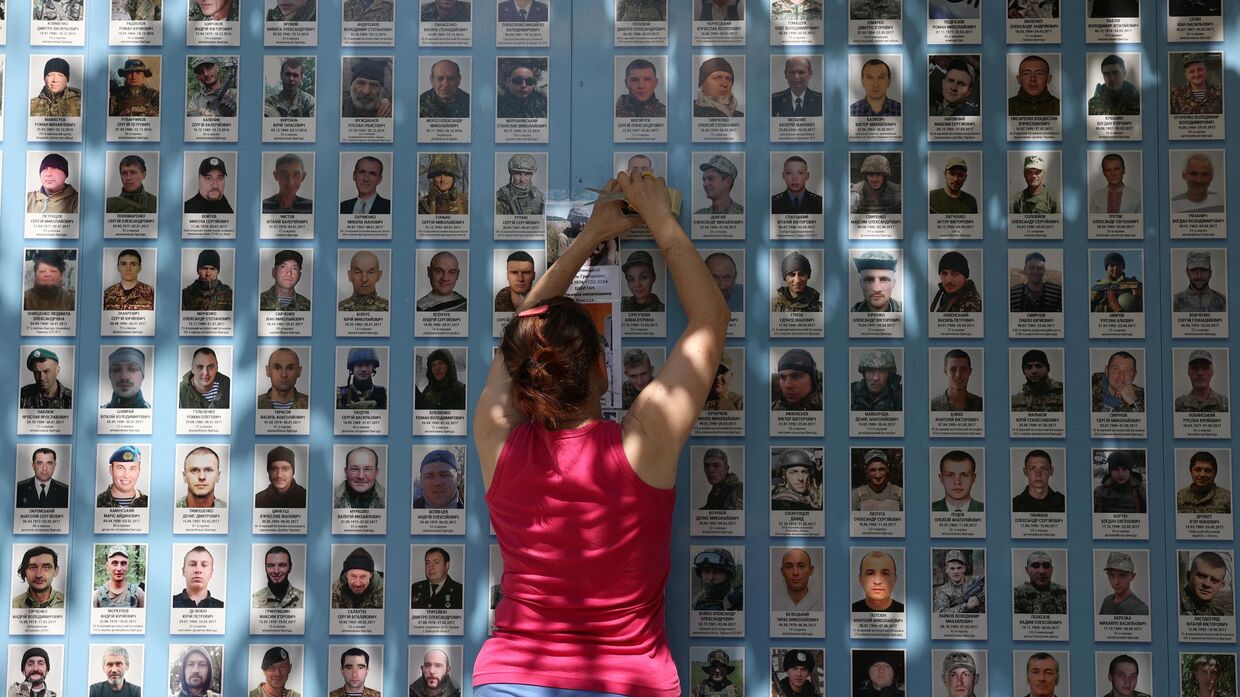 Женщина размещает портрет украинского солдата на Стене памяти павших за Украину в Киеве 30 июня 2024 года.