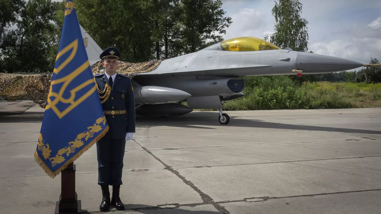 Украинский офицер стоит в почетном карауле на фоне истребителей F-16 Военно-воздушных сил Украины в неизвестном месте на Украине. 4 августа 2024 года