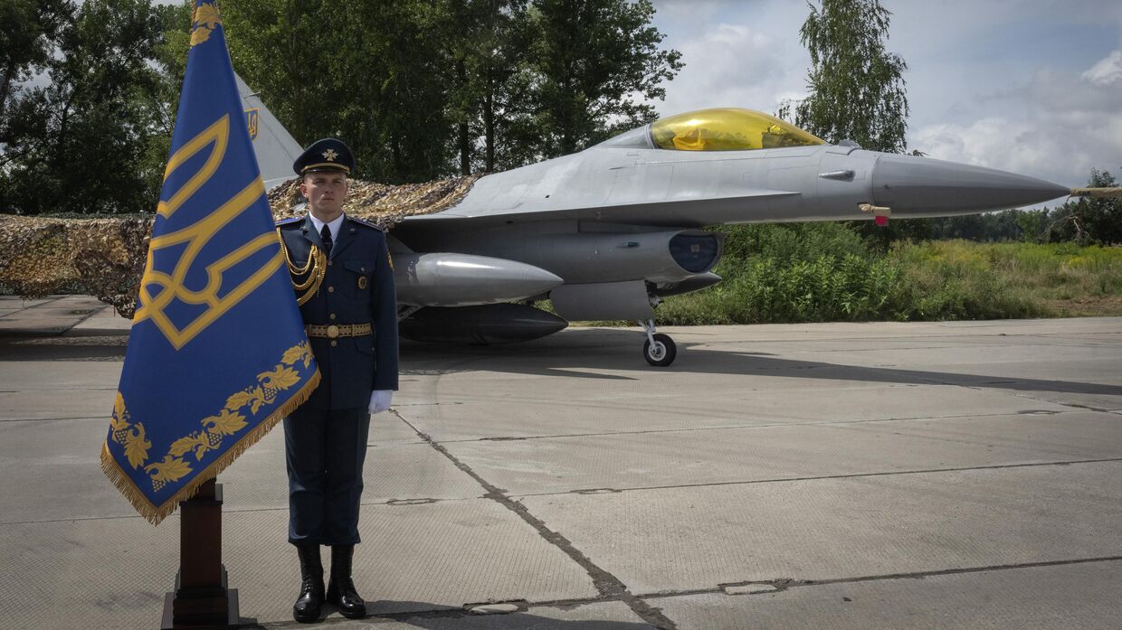 Украинский офицер стоит в почетном карауле на фоне истребителей F-16 Военно-воздушных сил Украины в неизвестном месте на Украине. 4 августа 2024 года