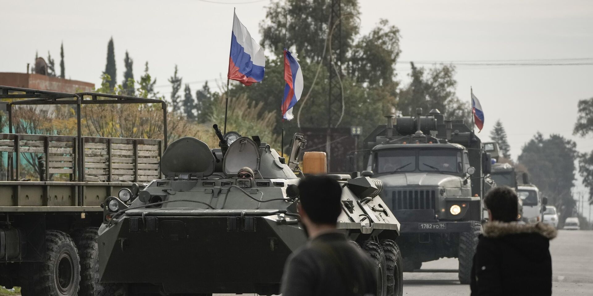 Сирийские боевики наблюдают за российской бронетехникой, проезжающей мимо авиабазы Хмеймим, которая в настоящее время находится под управлением России, в городе Хмеймим, Сирия, 16 декабря 2024 года. - ИноСМИ, 1920, 17.12.2024