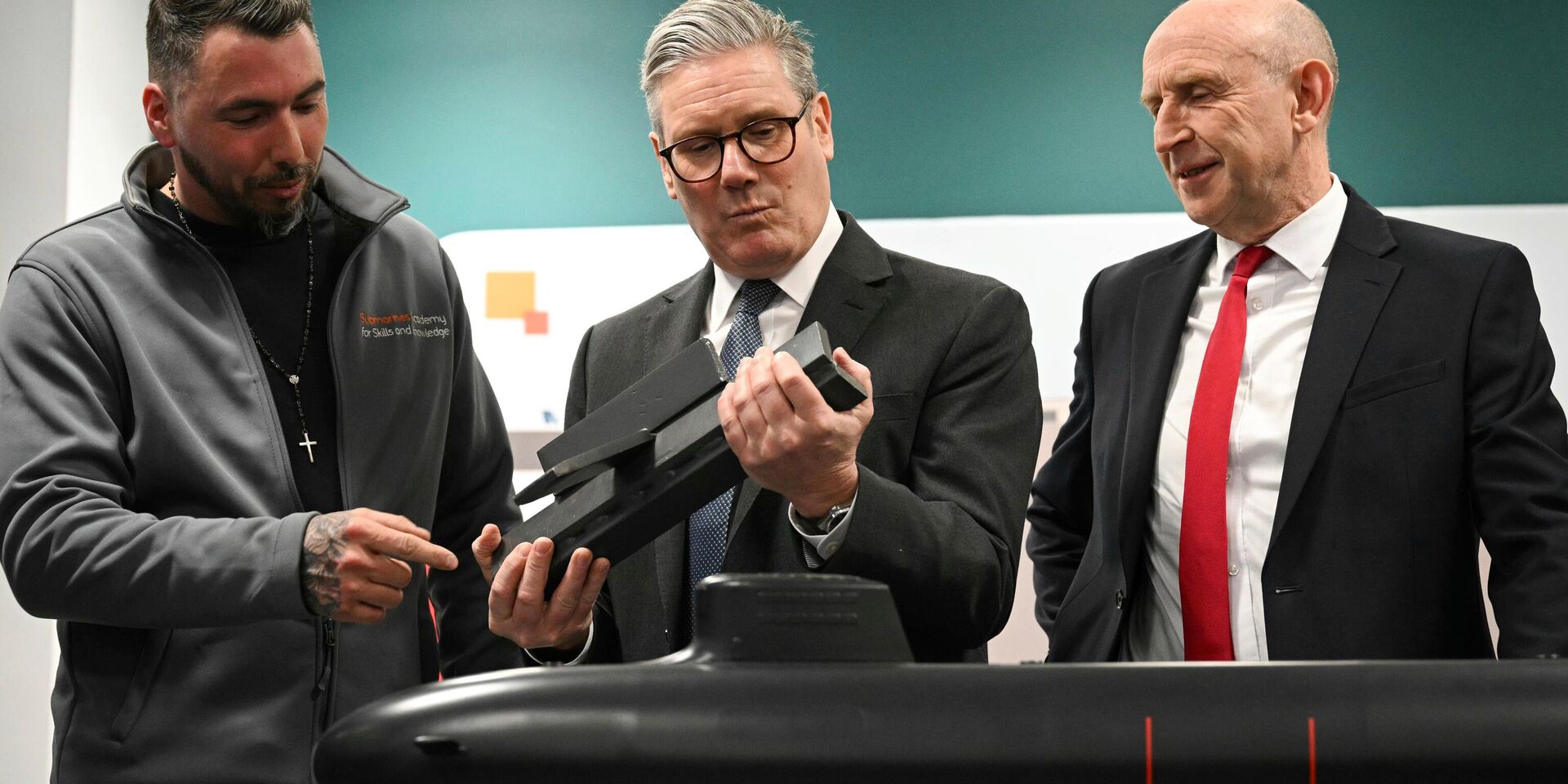 Премьер-министр Великобритании Кир Стармер (в центре) и министр обороны Джон Хили (справа) с сотрудником BAE system осматривают модель подводной лодки в Барроу-ин-Фернесс, Англия, 20 марта 2025 года. - ИноСМИ, 1920, 03.06.2025