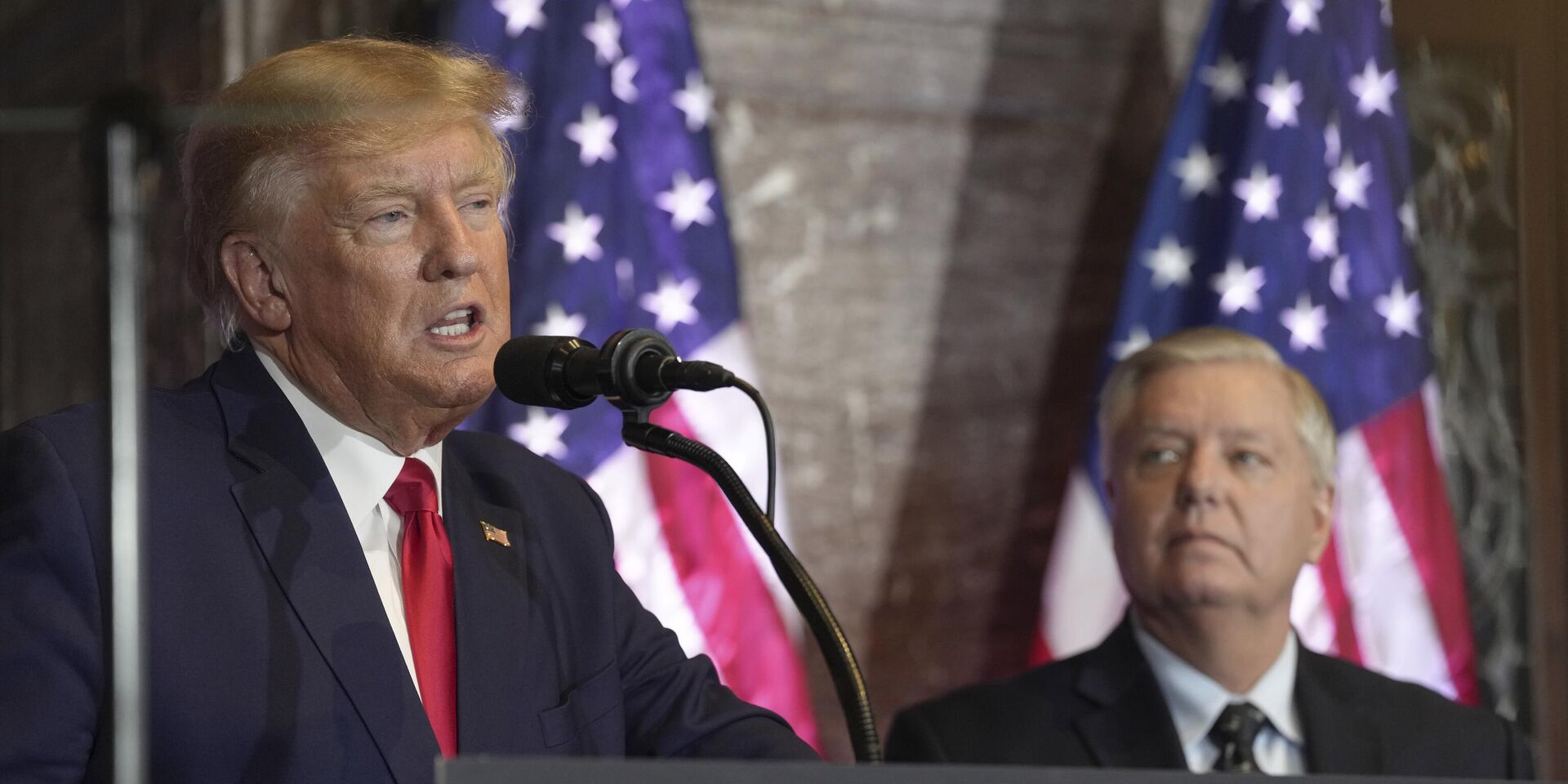 Дональд Трамп выступает на предвыборном мероприятии в законодательном собрании штата Южная Каролина 28 января 2023 года. Линдси Грэм слушает выступление. - ИноСМИ, 1920, 07.06.2025