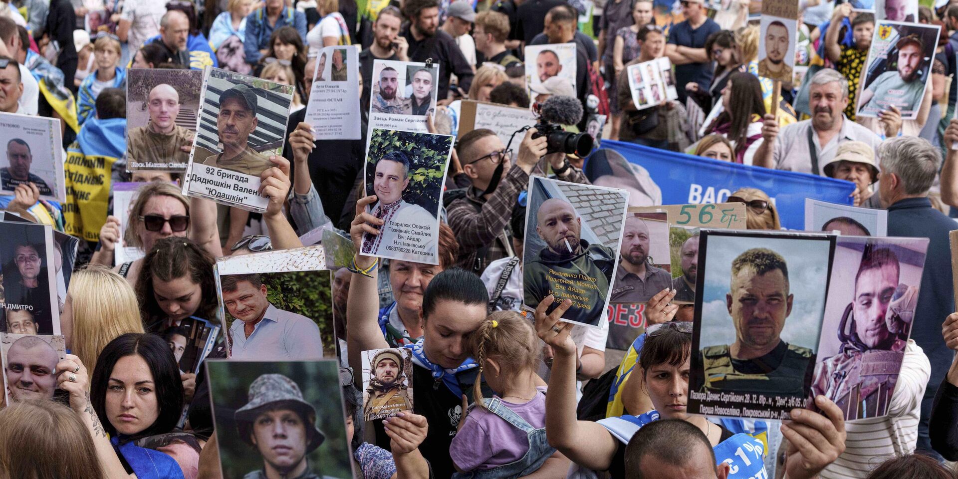 Украинцы держат в руках фотографии своих пропавших на фронте без вести родственников, встречая возвращающихся из плена солдат во время обмена между Россией и Украиной 9 июня 2025 года. - ИноСМИ, 1920, 17.06.2025