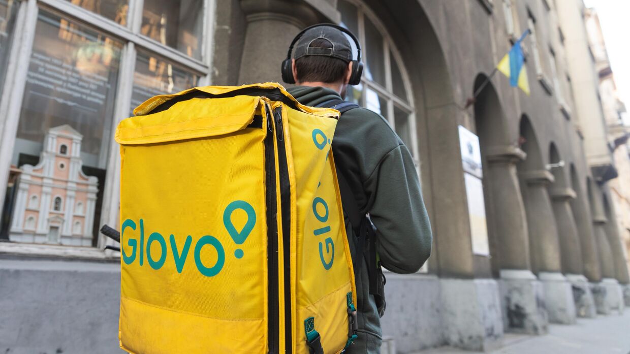 Курьер службы доставки еды Glovo на улице в старой исторической части Львова