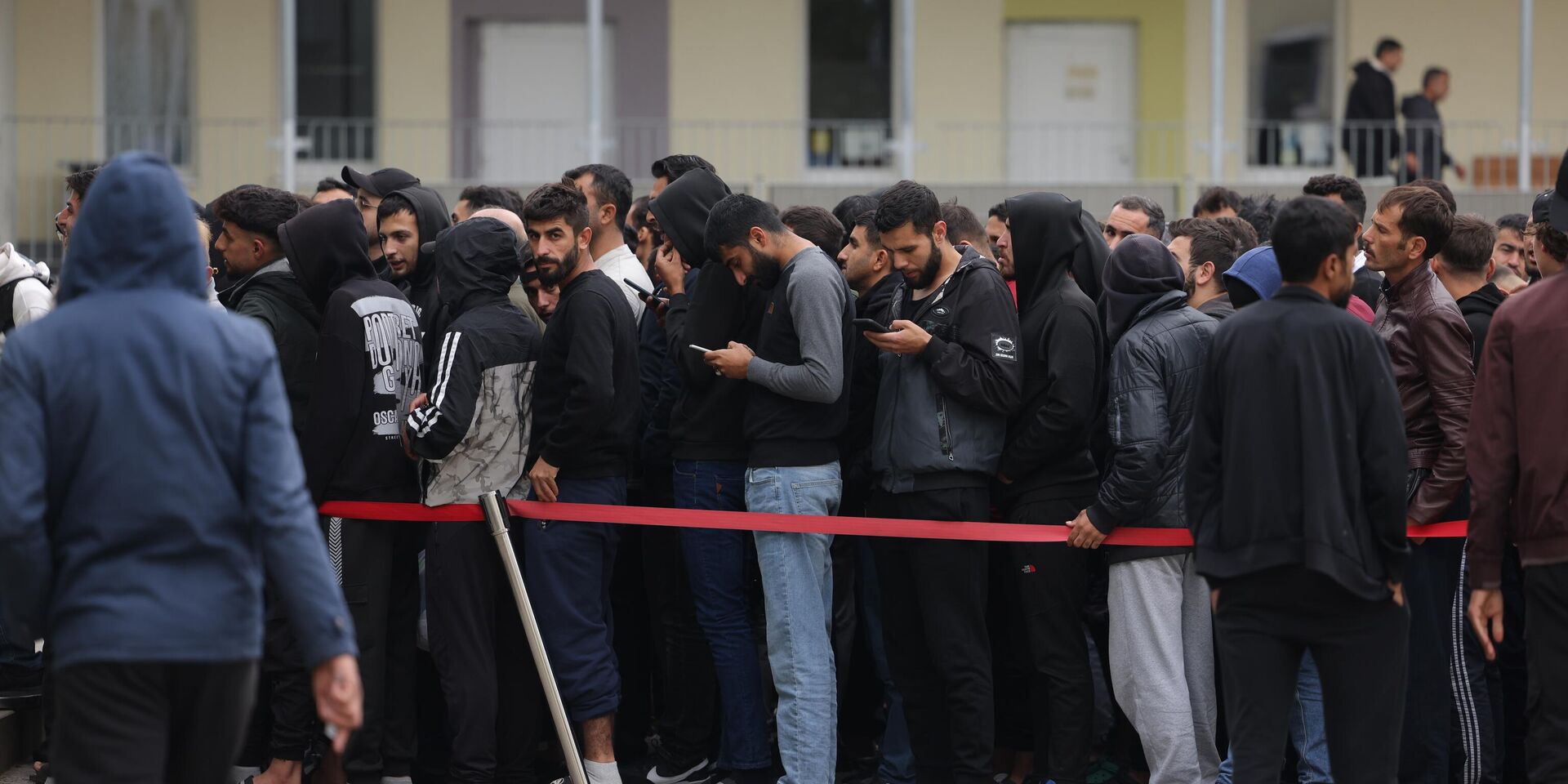 Германия  пытается приспособиться к высокому наплыву мигрантов. Мужчины, большинство которых из Сирии, стоят в очереди на обед в пункте первоначального приема мигрантов и беженцев в Айзенхюттенштадте - ИноСМИ, 1920, 27.06.2025