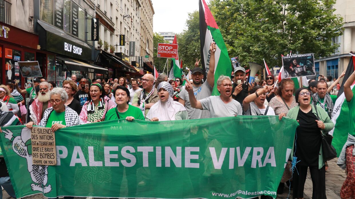 Люди с транспарантами, фотографиями и палестинскими флагами проходят маршем по центру Парижа в знак протеста против продолжающихся израильских атак на сектор Газа