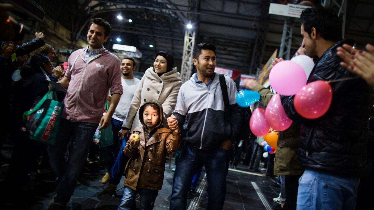 Местные жители приветствуют мигрантов по прибытии на главный железнодорожный вокзал Франкфурта-на-Майне, Германия