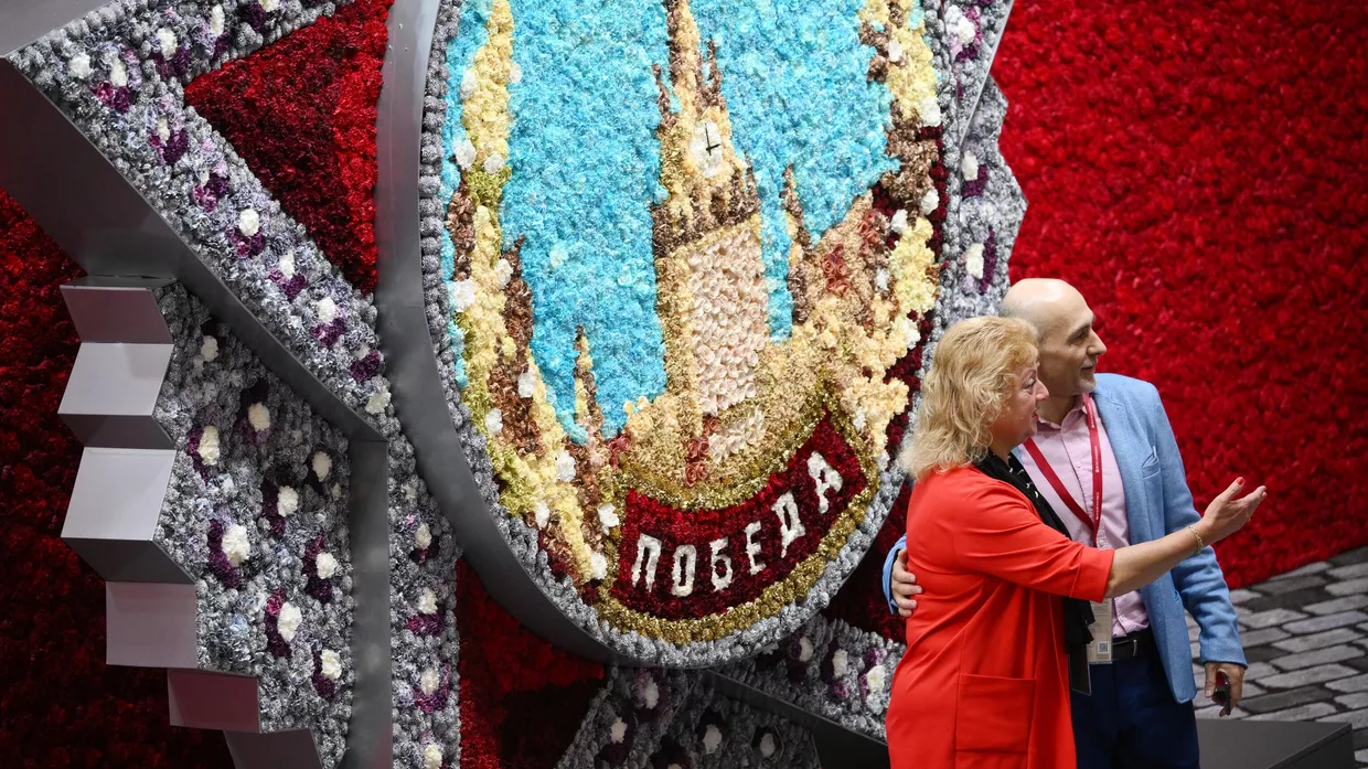 Посетители позируют рядом со стендом российского производителя удобрений Уралхим на Петербургском международном экономическом форуме 2025 года