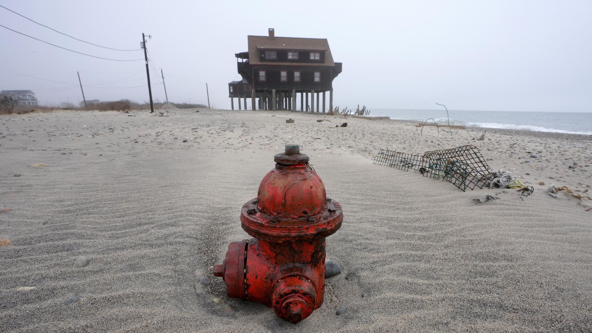 Полузасыпанный пожарный гидрант возле дома на опорах на пляже в Южном Кингстауне, штат Флорида. Эрозия и отступление береговой линии становятся все более распространенными явлениями из-за подъема уровня океана и изменения климата. - ИноСМИ, 1920, 06.08.2025