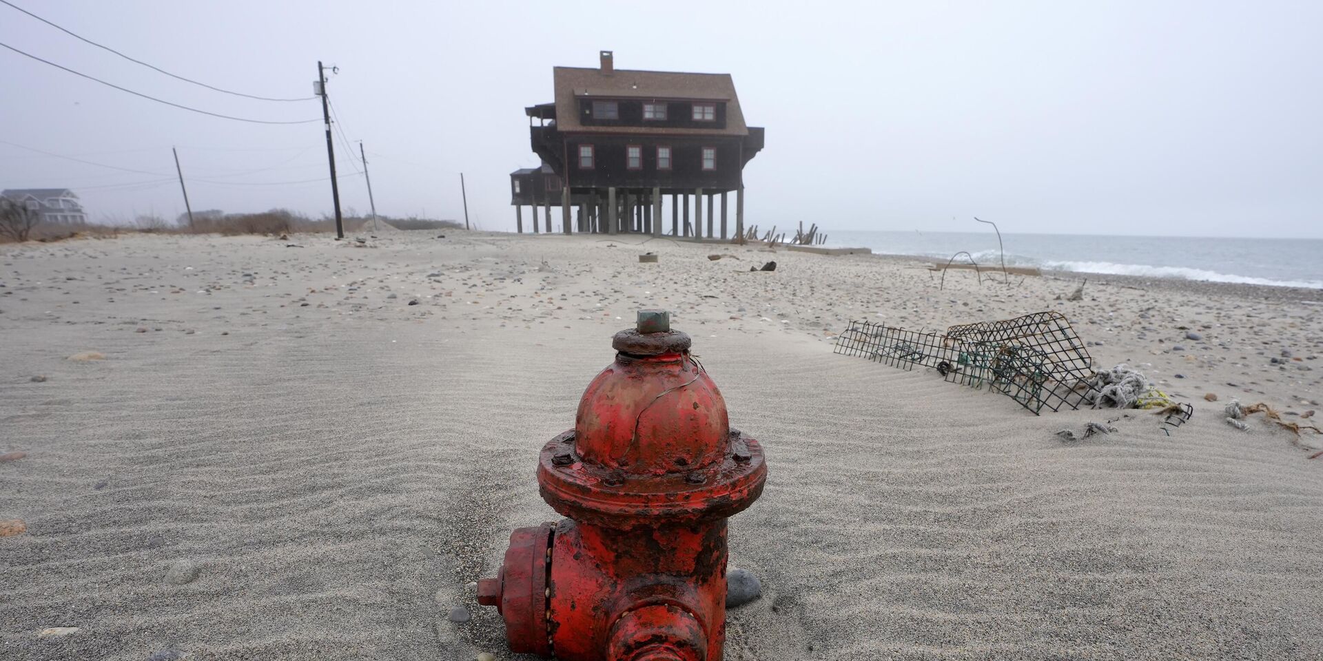 Полузасыпанный пожарный гидрант возле дома на опорах на пляже в Южном Кингстауне, штат Флорида. Эрозия и отступление береговой линии становятся все более распространенными явлениями из-за подъема уровня океана и изменения климата. - ИноСМИ, 1920, 06.08.2025