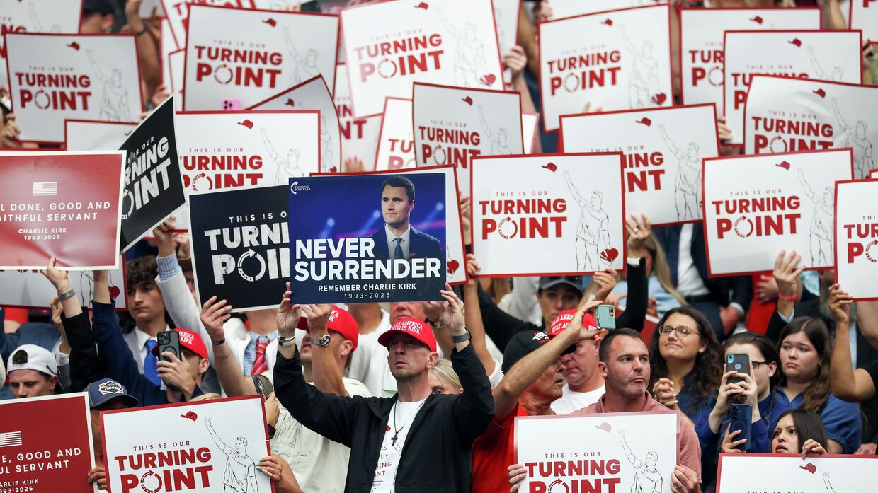 Участники с плакатами на траурной церемонии в память о политическом активисте Чарли Кирке в стадионе State Farm Stadium 21 сентября 2025 года в Глендейле, штат Аризона