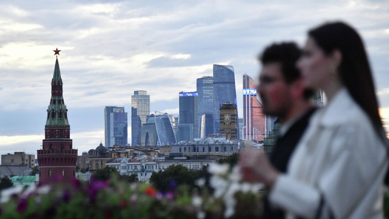 Молодой человек с девушкой идут по Большому Москворецкому мосту в Москве