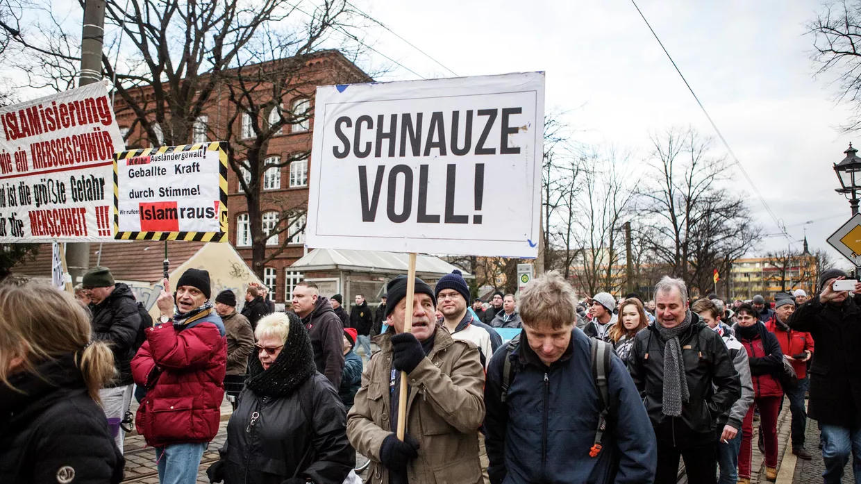 Участник с плакатом Я сыт по горло на акции протеста против большого числа беженцев, в основном мусульман, которые переехали в немецкий Котбус за последние годы