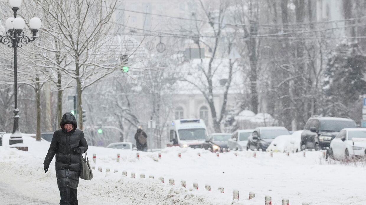 Женщина идет по заснеженным улицам Киева.