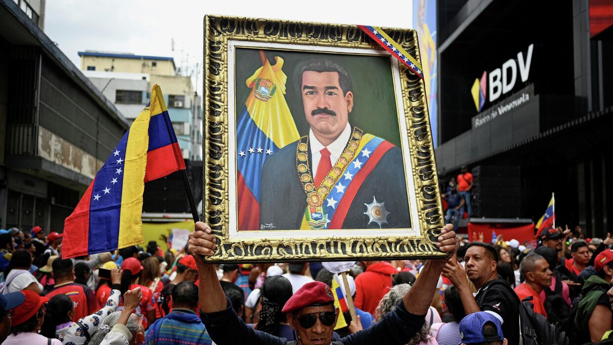 Демонстрант держит портрет президента Николаса Мадуро во время марша с требованием освободить Мадуро и его жену Силию Флорес, захваченных американскими войсками