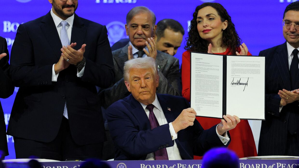 Президент США Дональд Трамп держит в руках подписанный Устав Совета мира в Давосе, Швейцария, 22 января 2026 года