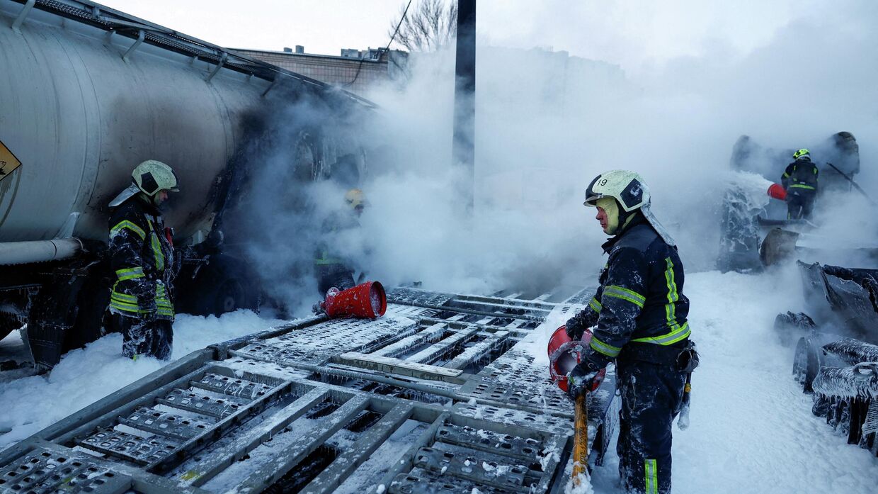 Пожарные тушат полуприцепы, поврежденные во время ночных ударов российских беспилотников и ракет в Киеве
