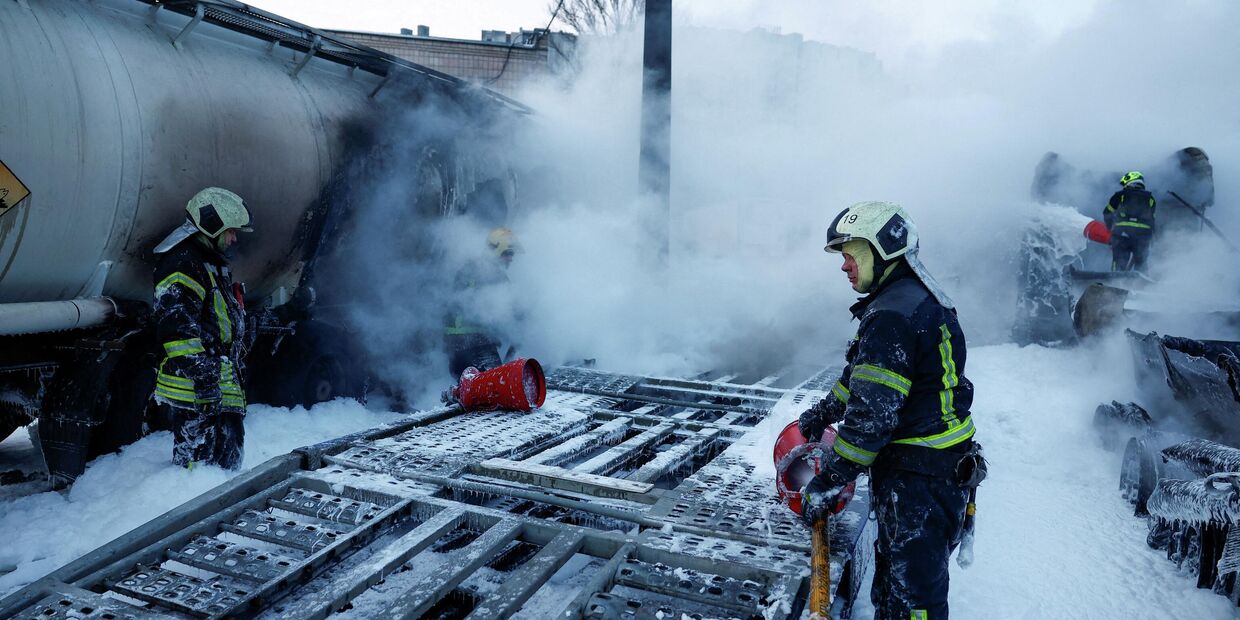 Пожарные тушат полуприцепы, поврежденные во время ночных ударов российских беспилотников и ракет в Киеве