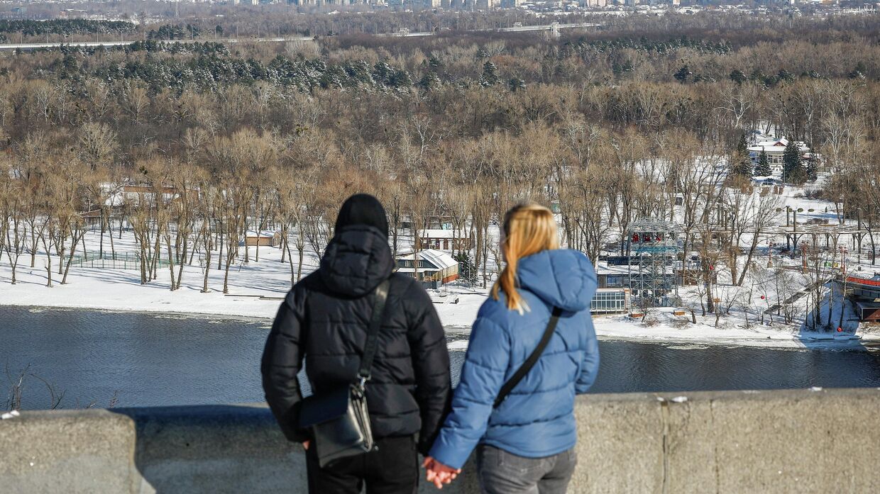 Пара смотрит на левый берег Днепра морозным зимним днем. Киев, 19 февраля 2026 года