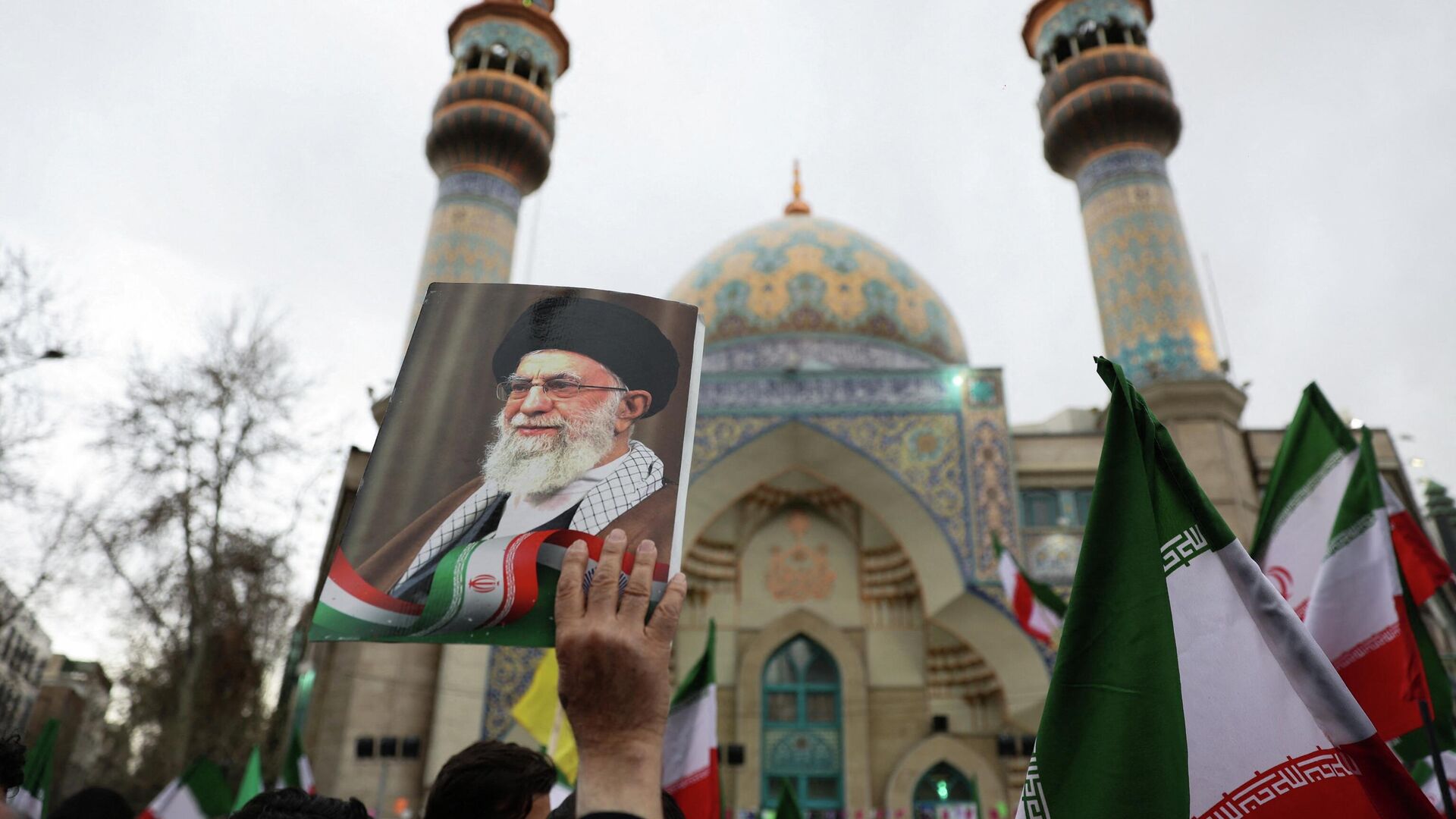 Человек держит в руках изображение верховного лидера Ирана аятоллы Али Хаменеи. Иранские демонстранты протестуют против американо-израильских ударов в Тегеране, 28 февраля 2026 года - ИноСМИ, 1920, 28.02.2026