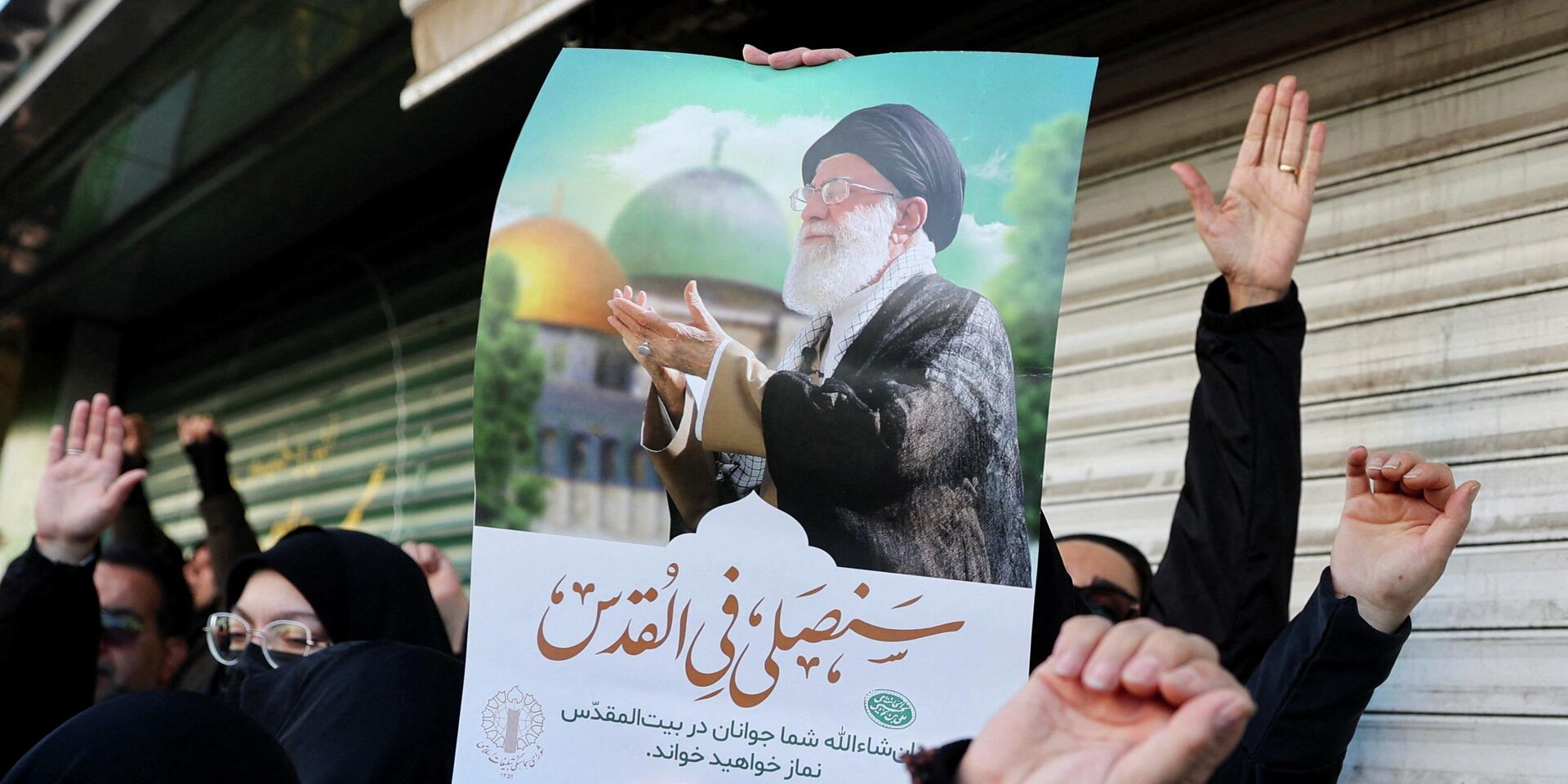 Женщина держит плакат с изображением верховного лидера Ирана аятоллы Али Хаменеи. Иранцы выходят на улицы оплакать смерть Хаменеи, убитого в результате ударов Израиля и США в субботу в Тегеране. Иран, 1 марта 2026 года - ИноСМИ, 1920, 02.03.2026