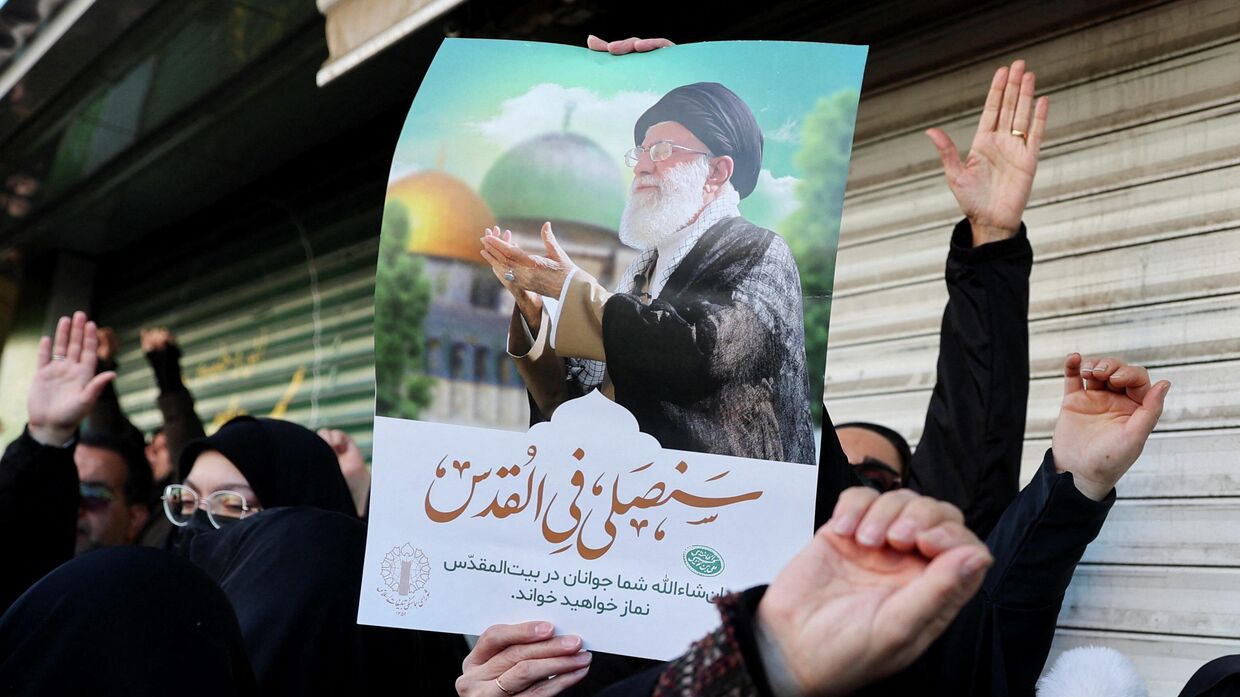 Женщина держит плакат с изображением верховного лидера Ирана аятоллы Али Хаменеи. Иранцы выходят на улицы оплакать смерть Хаменеи, убитого в результате ударов Израиля и США в субботу в Тегеране. Иран, 1 марта 2026 года