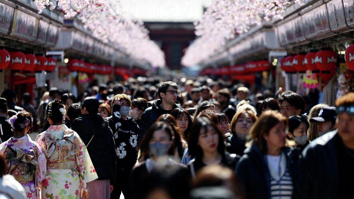 Посетители прогуливаются по улице Накамисэ-дори, посещая храм Сэнсо-дзи в районе Асакуса, популярном туристическом месте в Токио, Япония