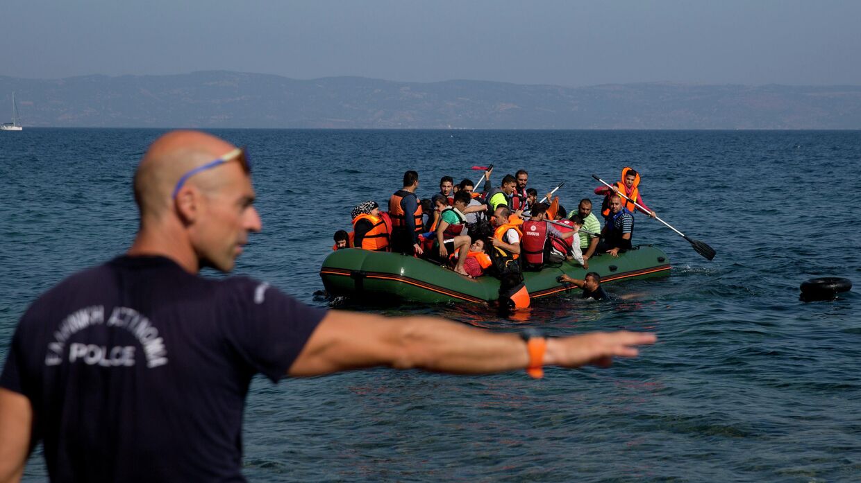 Греческий полицейский дает указания мигрантам у берега острова Лесбос