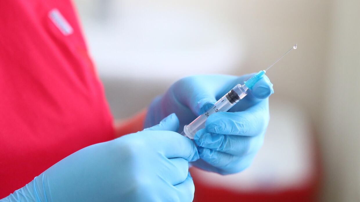 Медицинский работник держит шприц