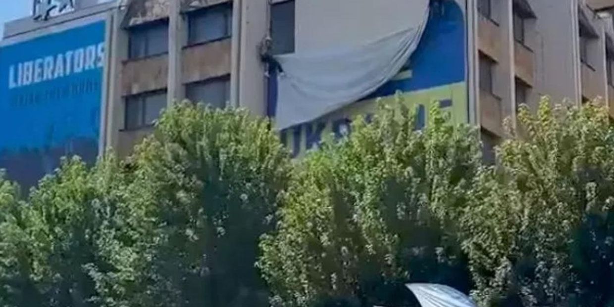 Рабочие снимают флаг Украины со здания в Приштине