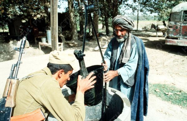 Находящийся в Афганистане советский солдат пьет воду из ведра местного жителя.
