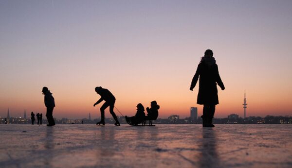 Германия, дети катаются на коньках на замерзшем озере.